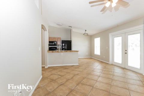 A spacious kitchen with a fan and tiled flooring.