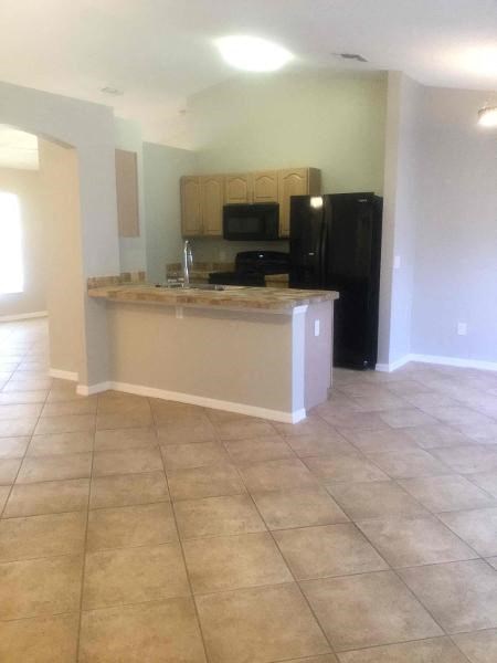 A kitchen with a black refrigerator and a countertop with a sink.