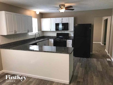 A kitchen with a black fridge and a black stove top.