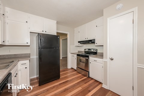 A kitchen with white cabinets and a black fridge.