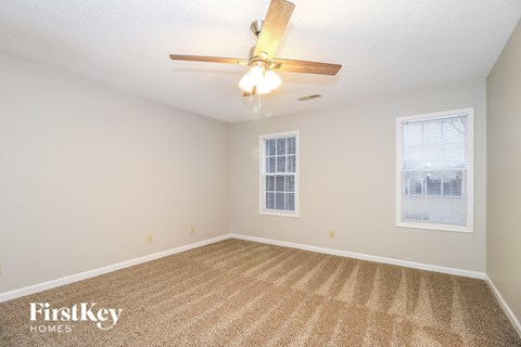 a spacious living room with carpet and a ceiling fan
