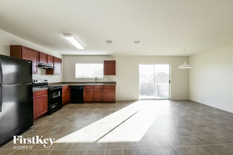A kitchen with a black fridge and wooden cabinets.