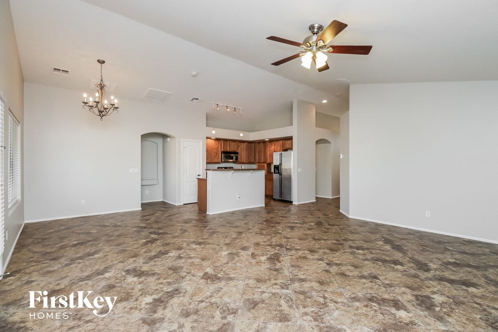 a kitchen and living room with white walls and a ceiling fan