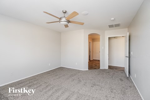 a spacious living room with carpet and a ceiling fan