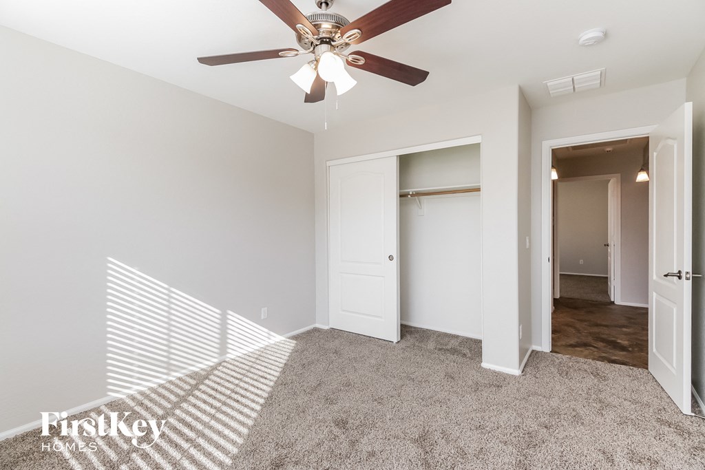 a bedroom with a ceiling fan and a closet