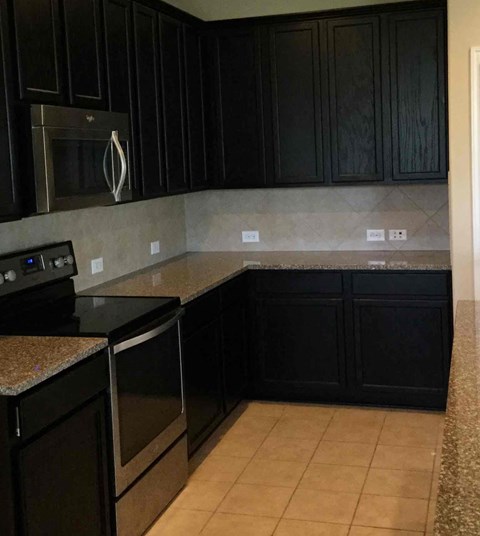 A kitchen with black cabinets and a granite countertop.