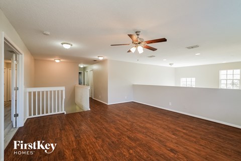 the living room and dining room with wood flooring and a ceiling fan