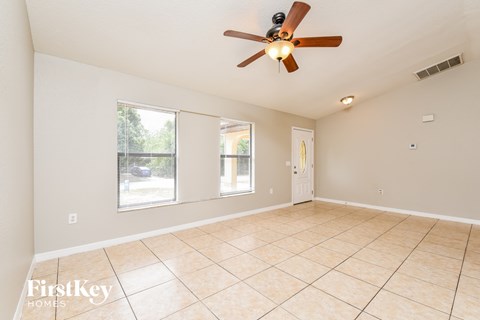 A spacious room with a ceiling fan and tiled flooring.
