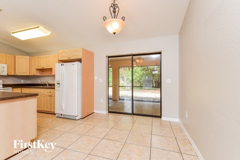 A kitchen with a refrigerator, cabinets, and a chandelier.