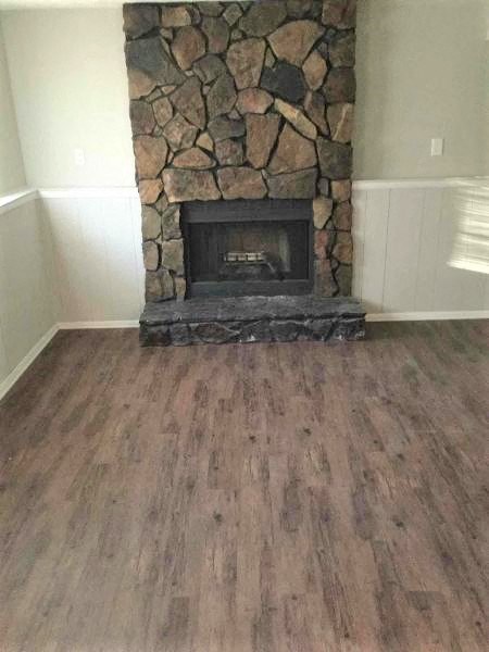 a living room with a stone fireplace and a wooden floor