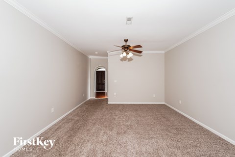 a spacious living room with carpet and a ceiling fan