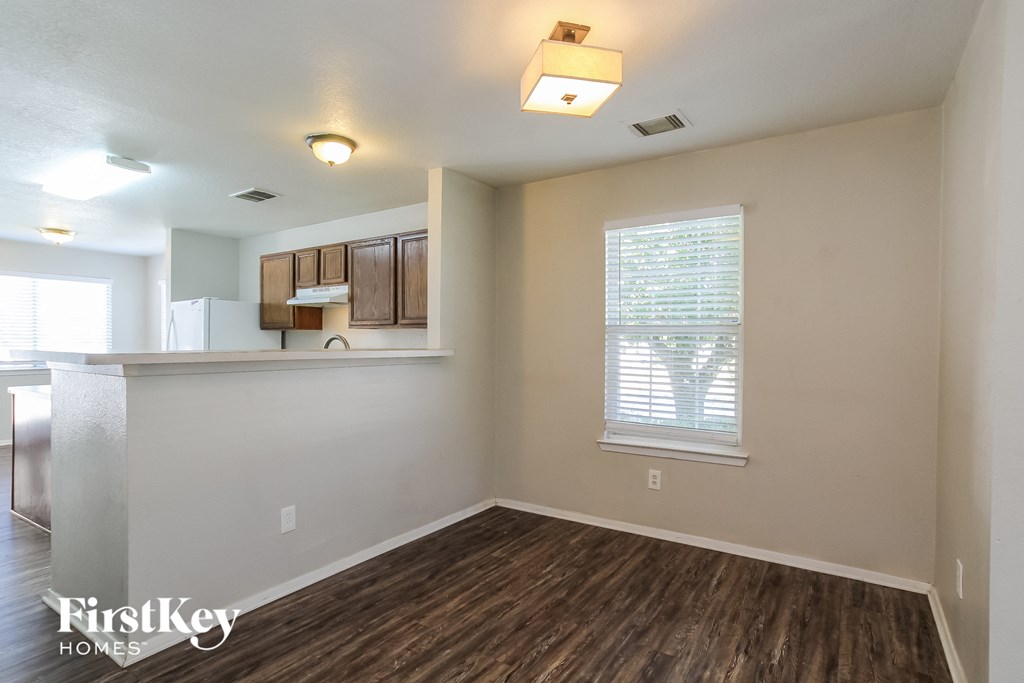 the living room and kitchen of an apartment with wood flooring and a window