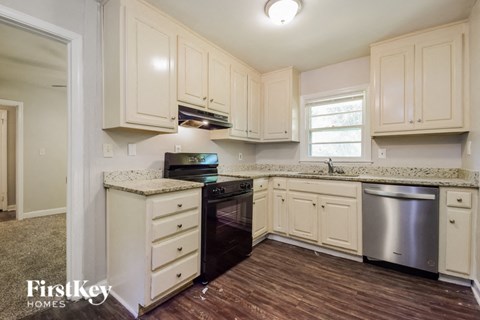 a kitchen with white cabinets and black appliances and a wooden floor