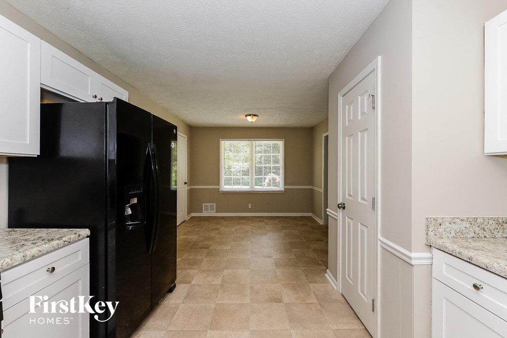 a kitchen with white cabinets and a black refrigerator     and a window