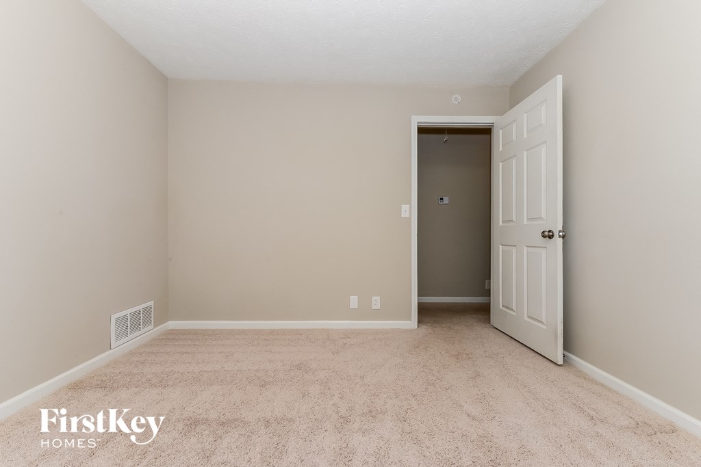 a bedroom with a white door and a carpeted floor