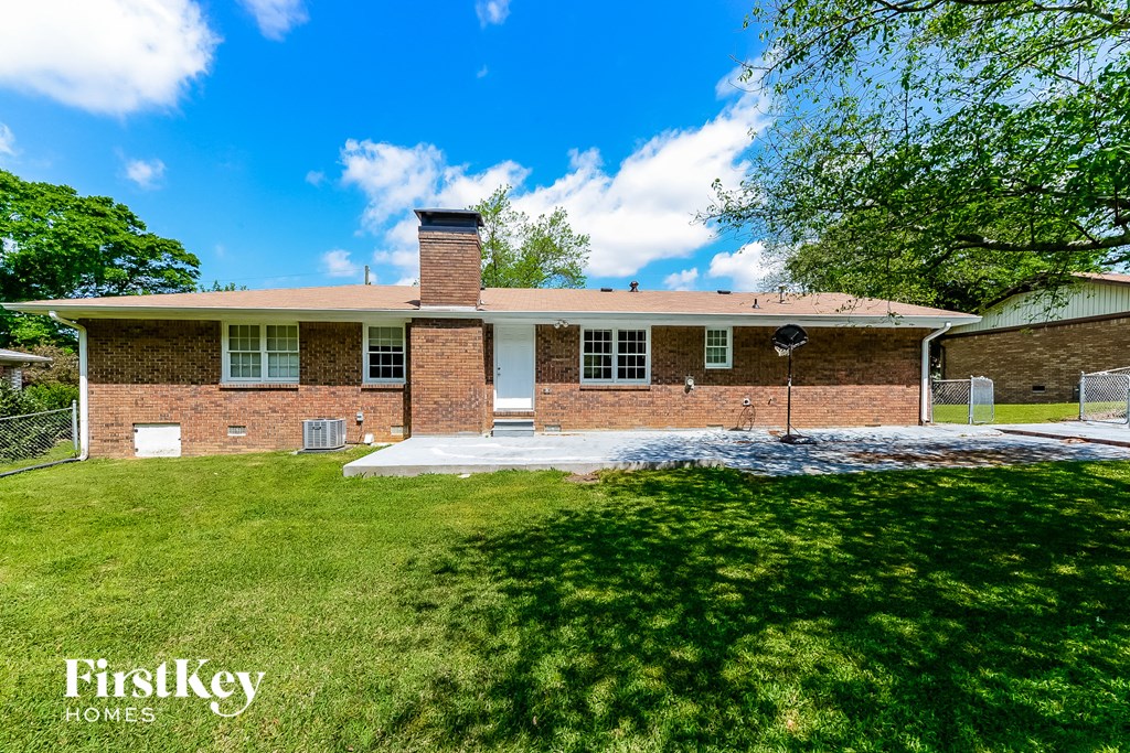 the front of a brick house with a yard and grass