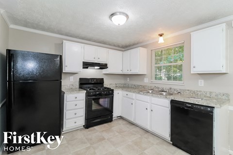 a white kitchen with black appliances and white cabinets