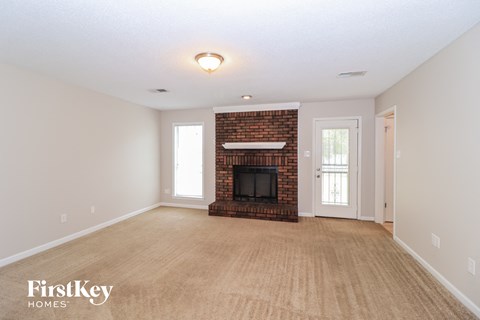 A living room with a fireplace and a door leading to another room.