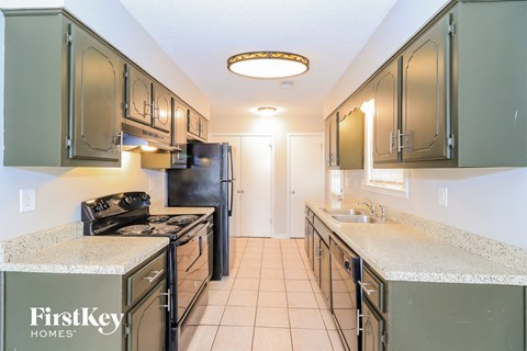 A kitchen with green cabinets and a black refrigerator.