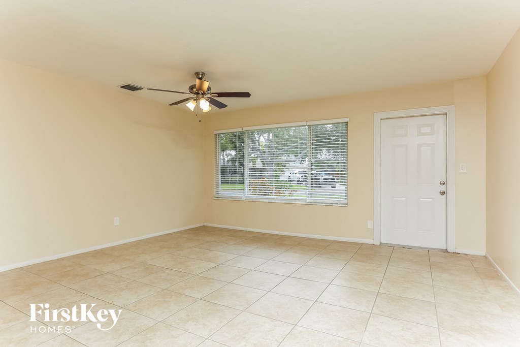 an empty living room with a ceiling fan and a window