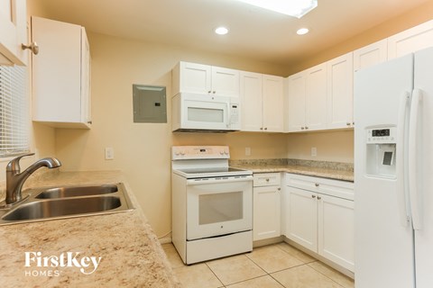 a kitchen with white cabinets and appliances and granite counter tops