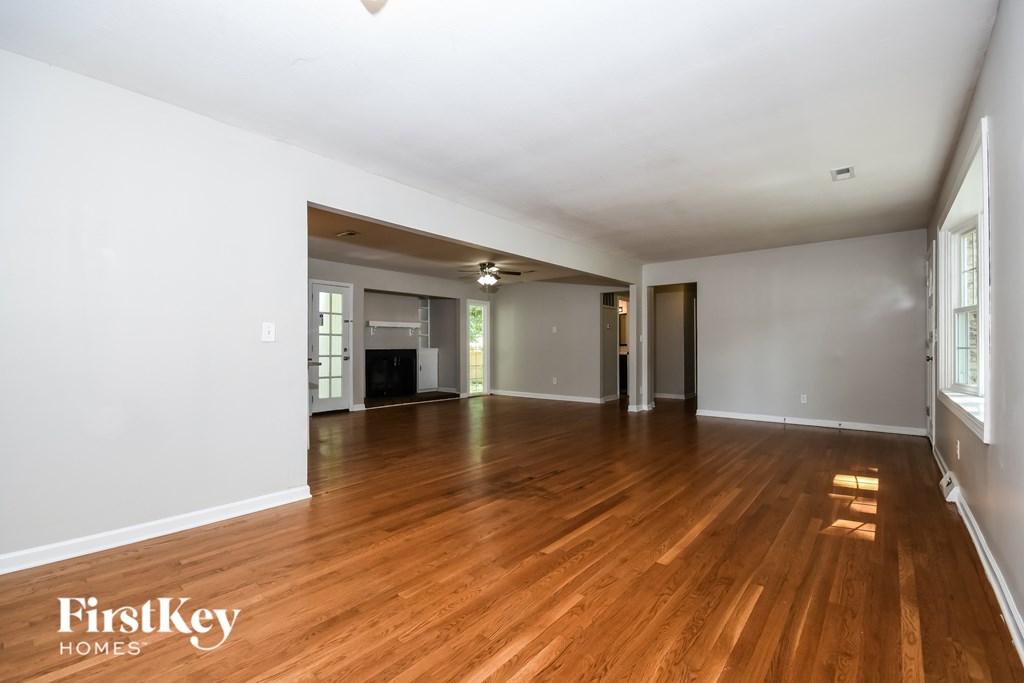 A spacious room with wooden flooring and white walls.