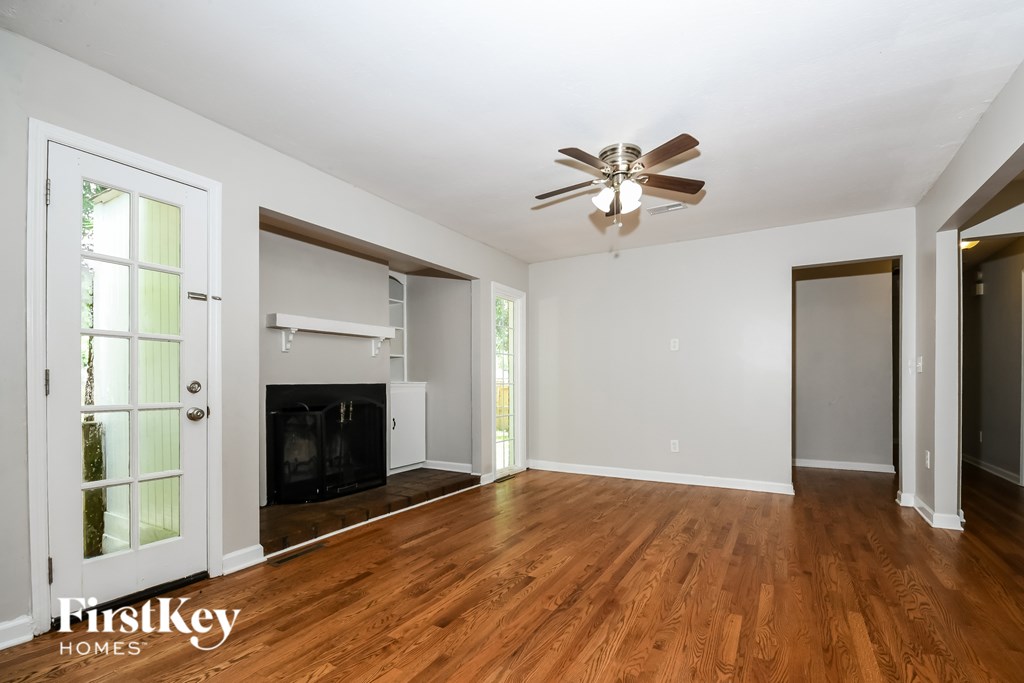 A spacious room with a fireplace and a ceiling fan.