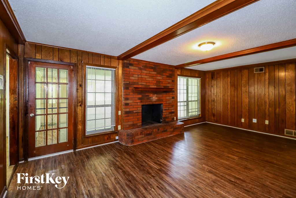 the living room of a house with a brick fireplace and wooden floors