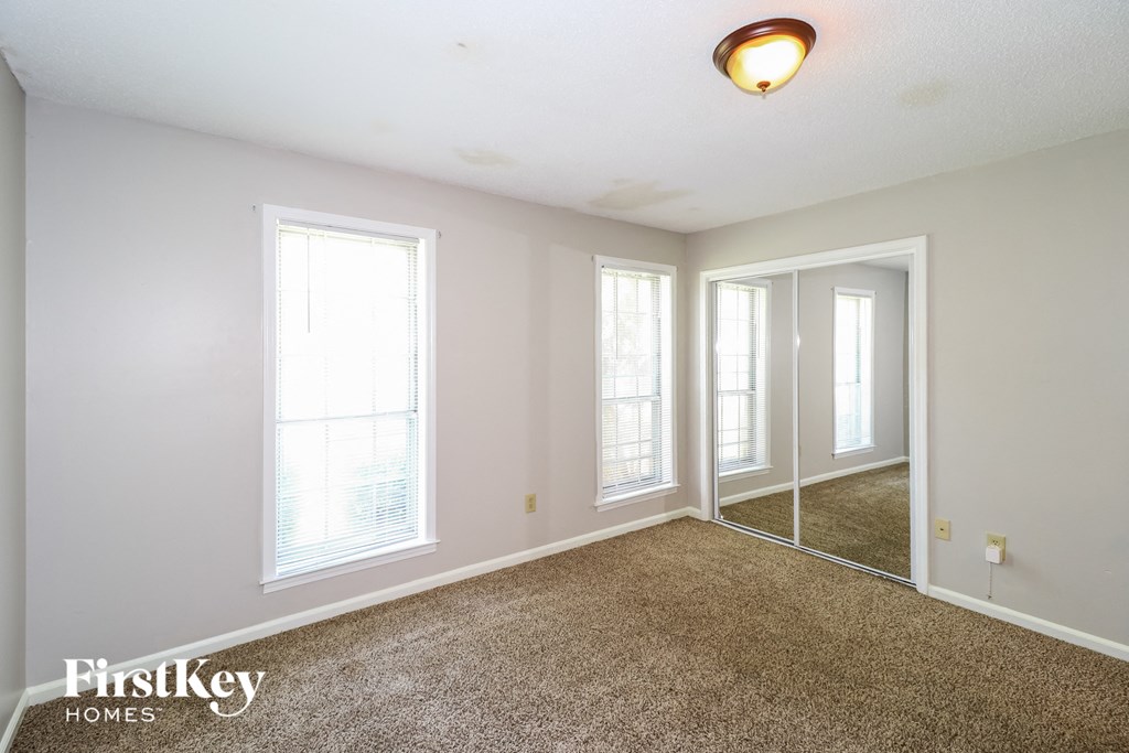 a bedroom with three windows and a carpeted floor