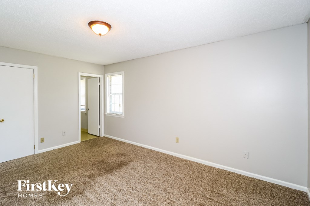 a spacious living room with carpet and a door to the bathroom