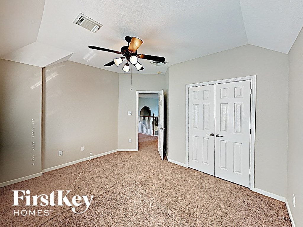 A room with a carpet floor and a ceiling fan.