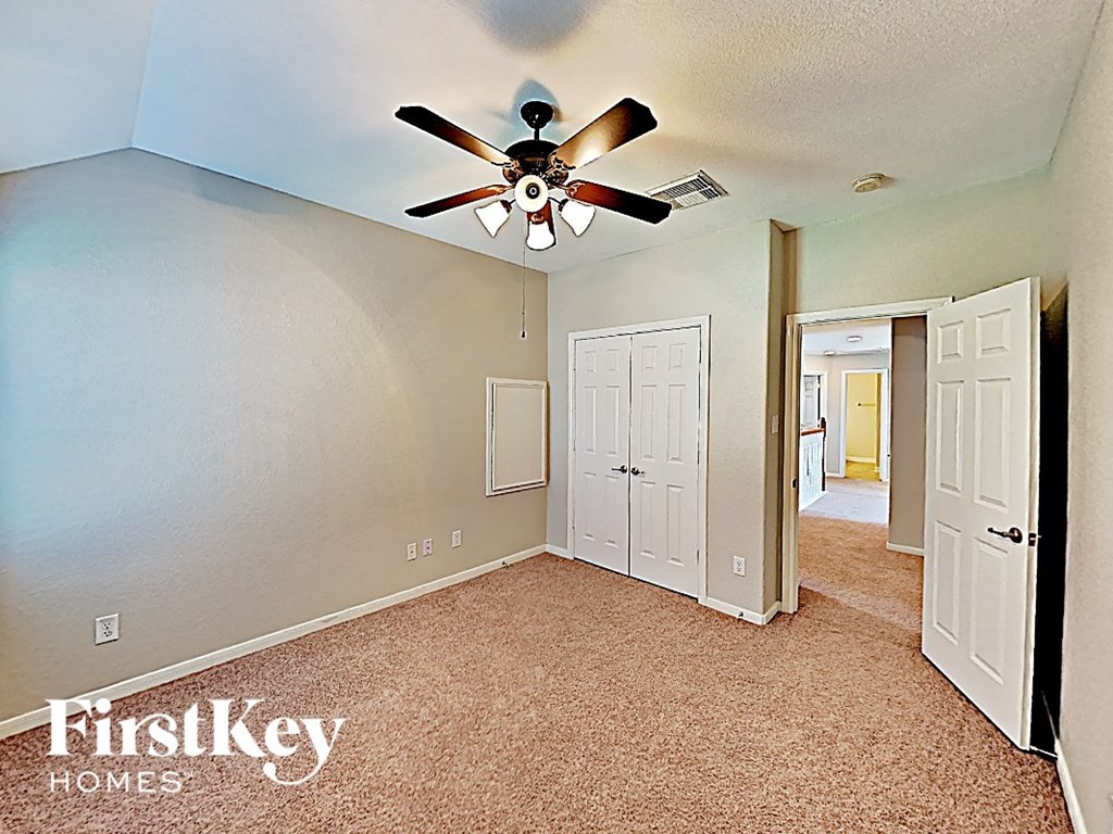 A room with a ceiling fan and a carpeted floor.