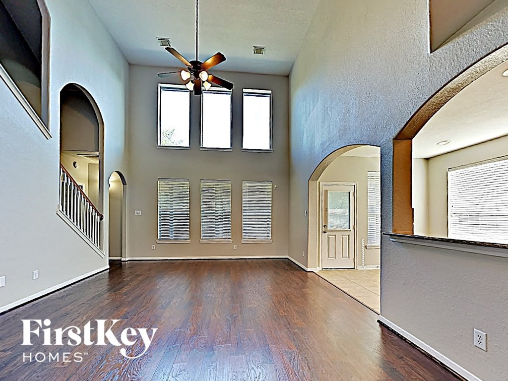 A spacious room with a fan and wooden floors.