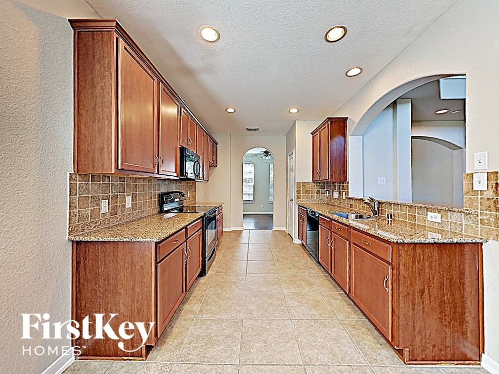 A kitchen with brown cabinets and a tile floor.