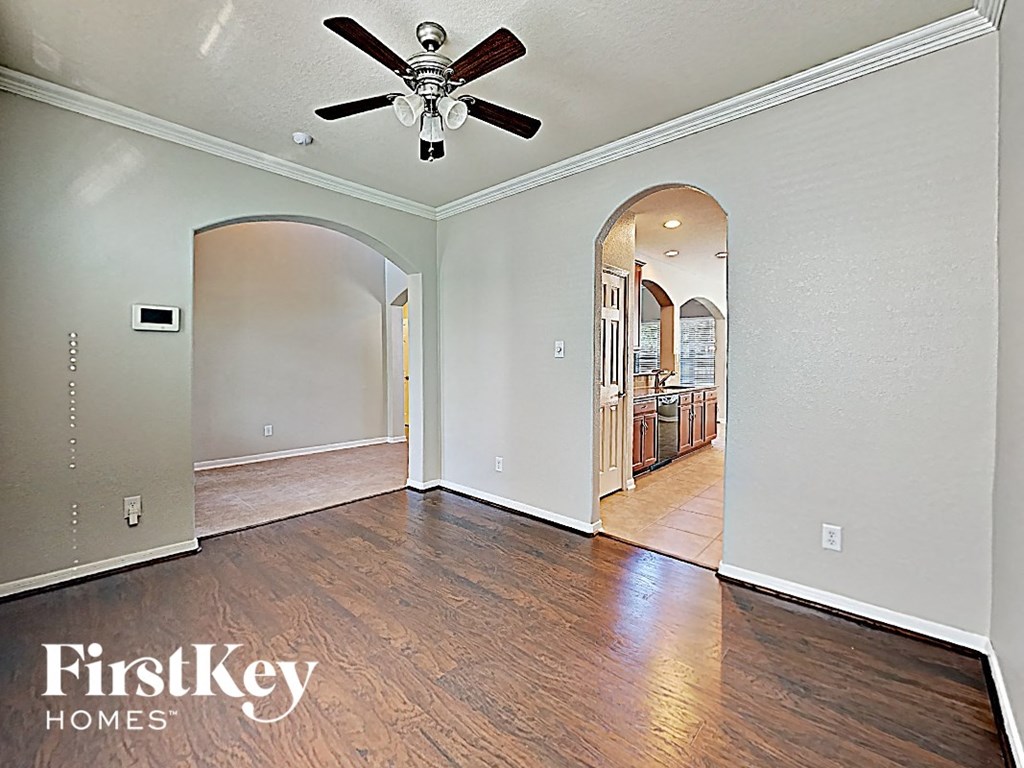 A spacious room with a ceiling fan and wooden flooring.