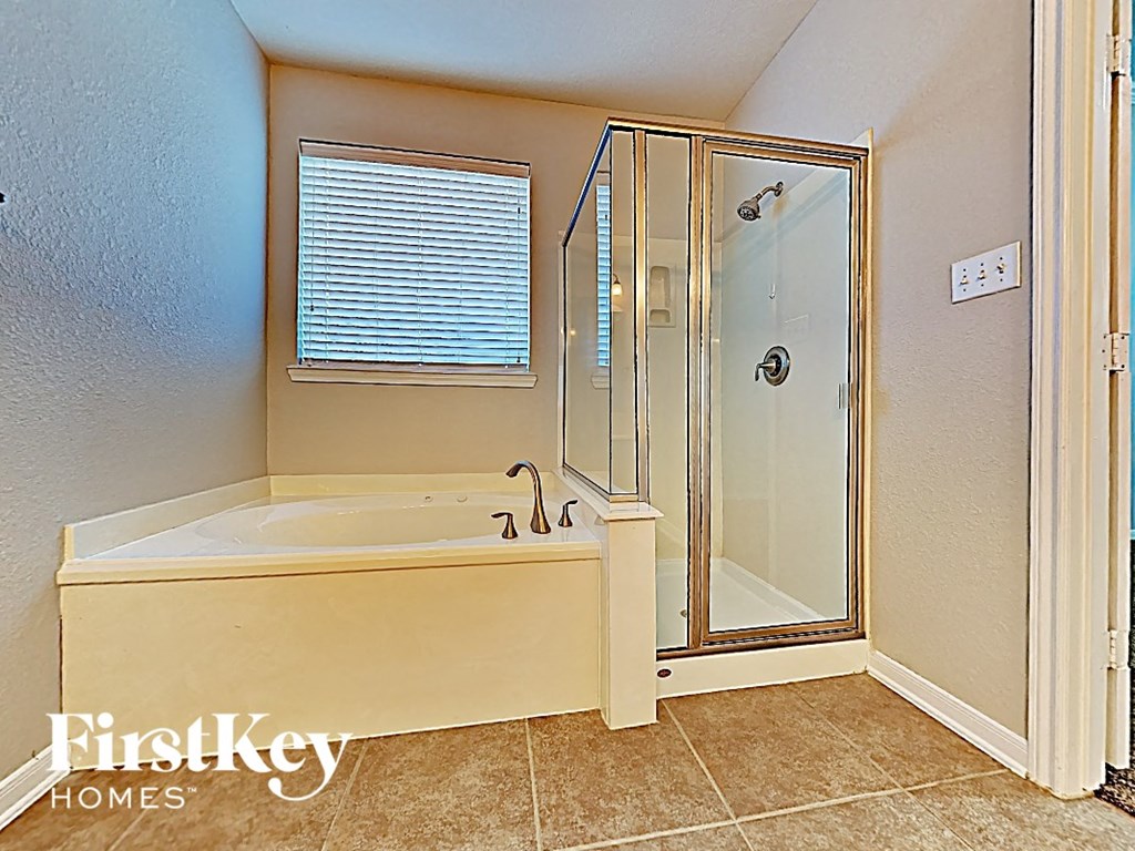 A bathroom with a beige tub and a glass shower door.