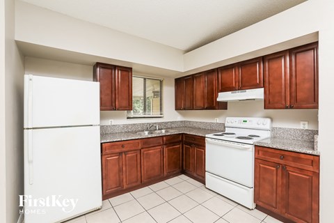 A kitchen with white appliances and brown cabinets.