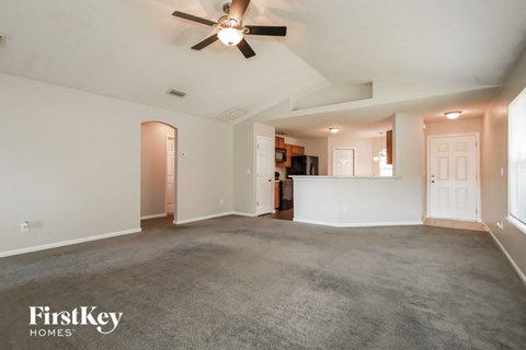 A spacious room with a ceiling fan and carpeted floor.