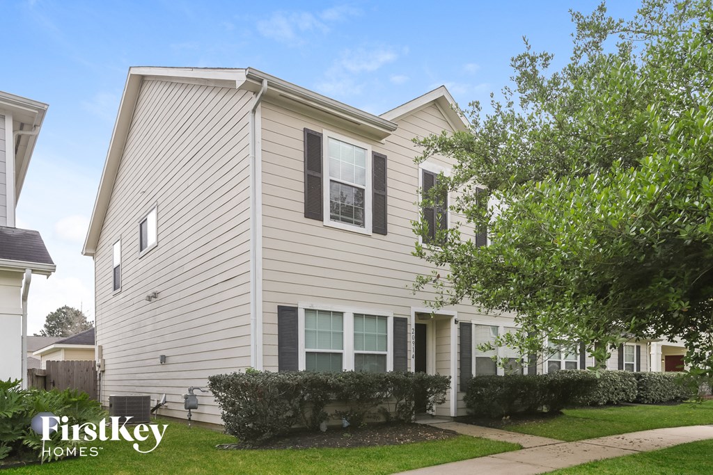 a white house with a sidewalk and trees in front of it