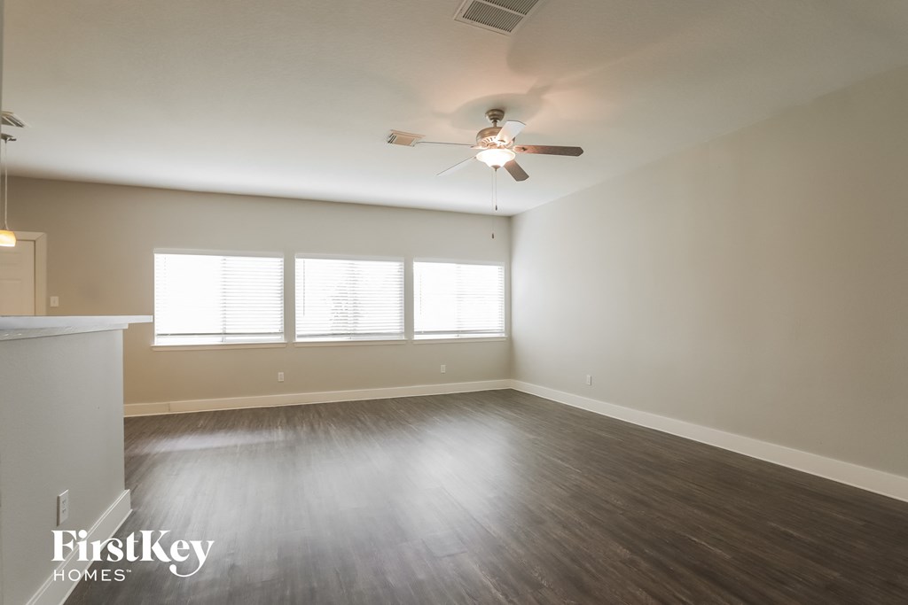 an empty living room with wood floors and a ceiling fan