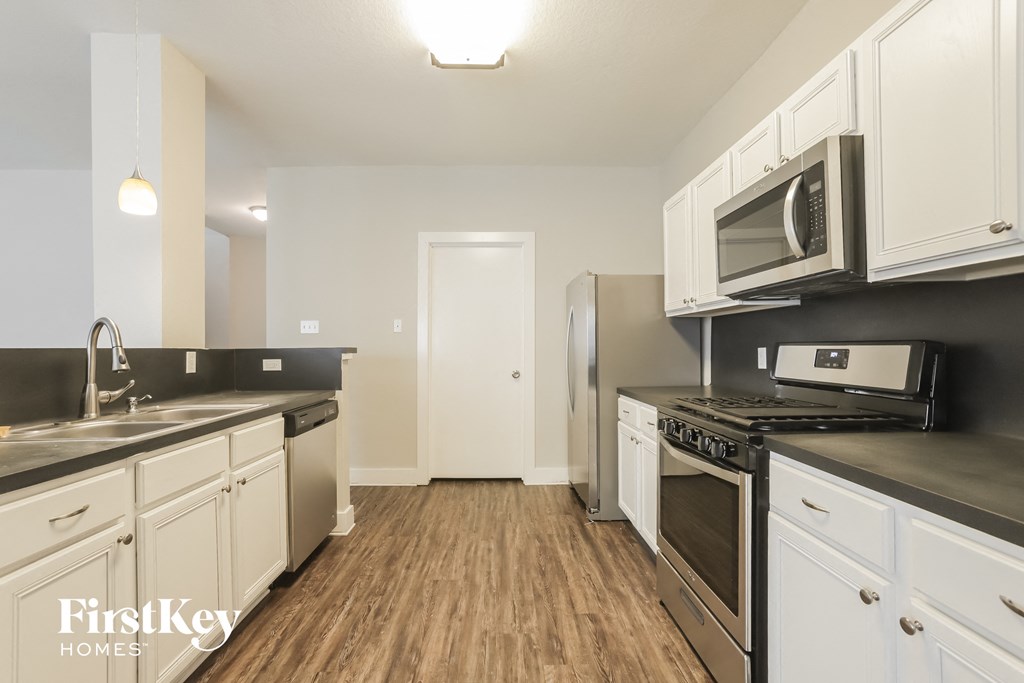 a kitchen with white cabinets and stainless steel appliances and a wood floor