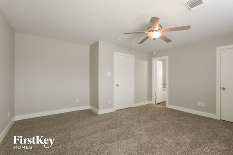 a spacious living room with carpet and a ceiling fan