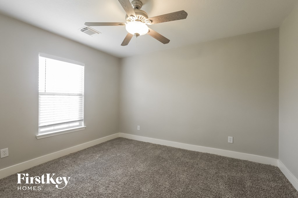 an empty room with a ceiling fan and a window