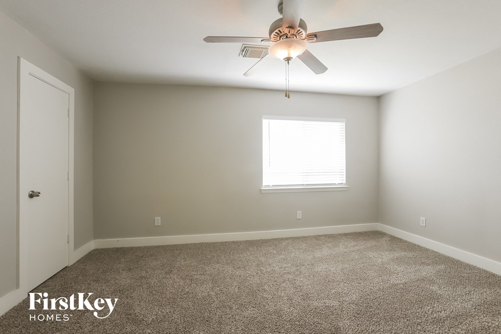 a carpeted room with a ceiling fan and a window