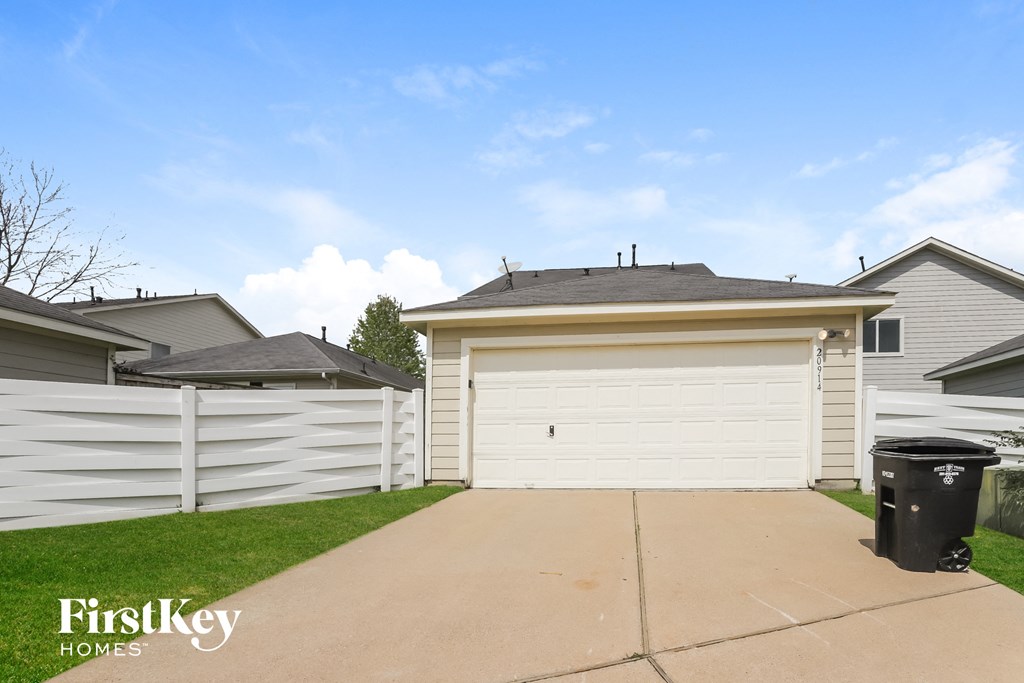 a white garage with a white fence and a driveway
