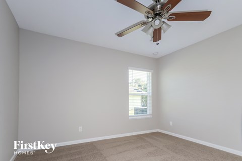 a living room with a ceiling fan and a carpet
