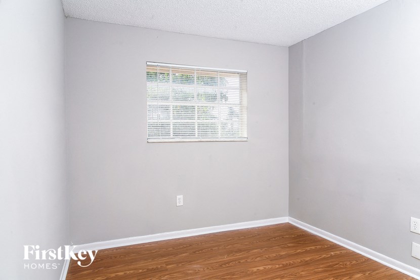 a bedroom with a window and wooden floors