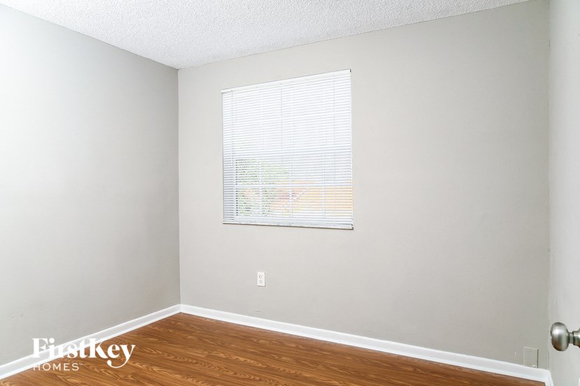 a bedroom with wood floors and a window