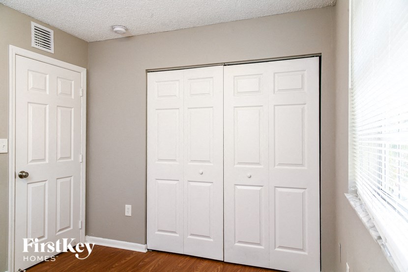 a bedroom with two closets and a window with white doors