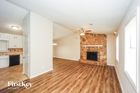 A spacious room with a fireplace and wooden flooring.